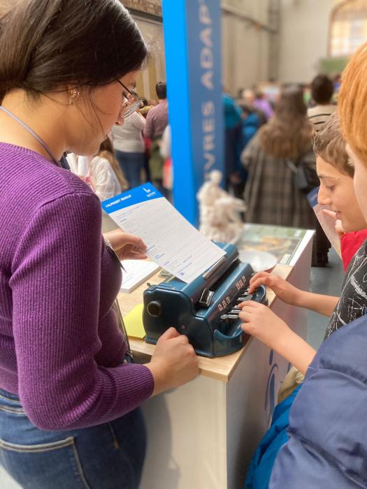 Een kind test brailleschrift op een beurs.